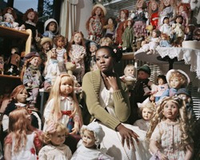 Dunkelhäutige Frau inmitten zahlreicher Puppen