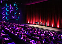 Ein Blick durch den vollbesetzten großen Kinosaal auf die Bühne mit Schauspielern und Crew bei der Premiere von 'Lakritz' im Oktober 2019. Foto: Stadt Münster
