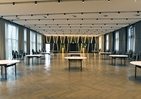 Das Atlantic-Hotel Münster: großer Veranstaltungssaal mit Parkettboden, beidseitig Fensterfronten mit Vorhängen