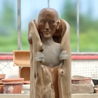 Holz-/Alabasterfigur, die sich aus einem umgebenden Holzmantel befreit
