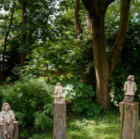 Drei Keramikfiguren auf Holzstämmen