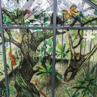 Gläsernes Gewächshaus mit bunten Bildern von Pflanzen und Tieren an den Glaswänden