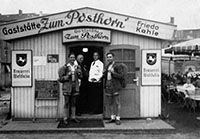 Vier Männer stehen vor einem Hozhäuschen mit dem Schild "Gaststätte Zum Posthorn"