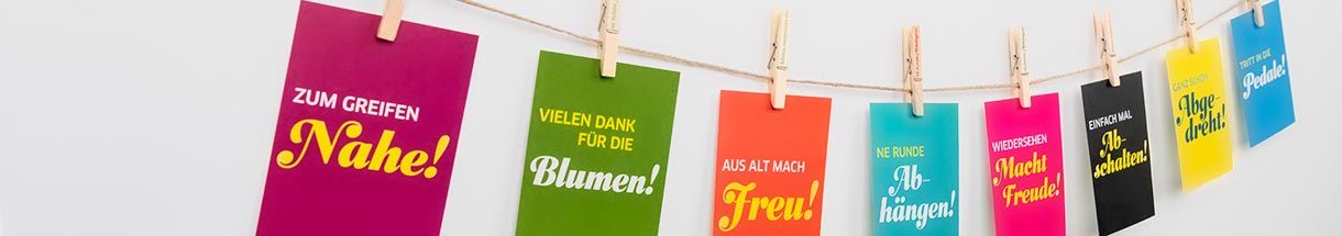 Postkarten mit Klimaschutz-Slogans sind mit Wäscheklammern an einer Leine befestigt.