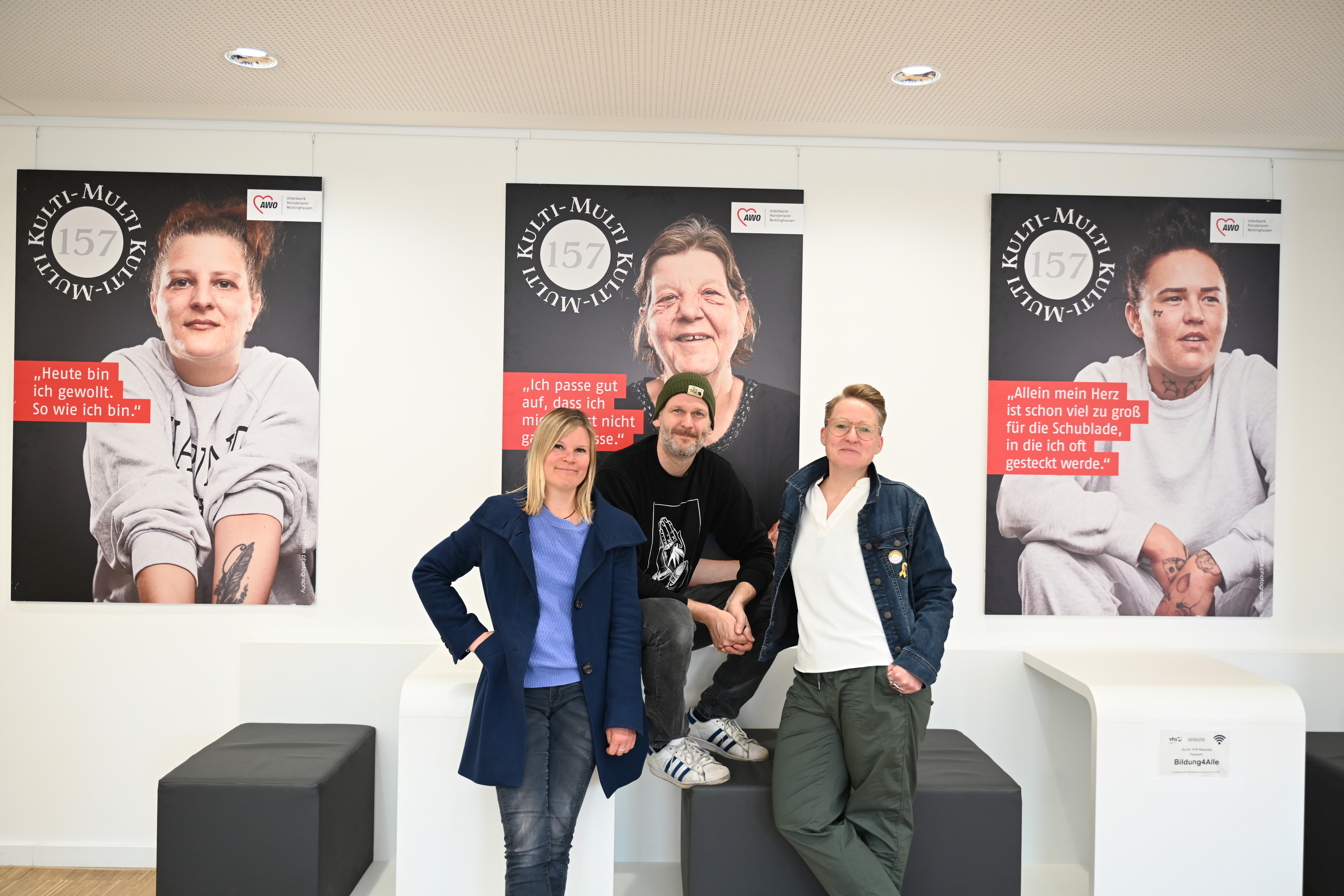 Drei Personen vor Großplakaten mit Porträts von Frauen aus dem Stadtteil Coerde
