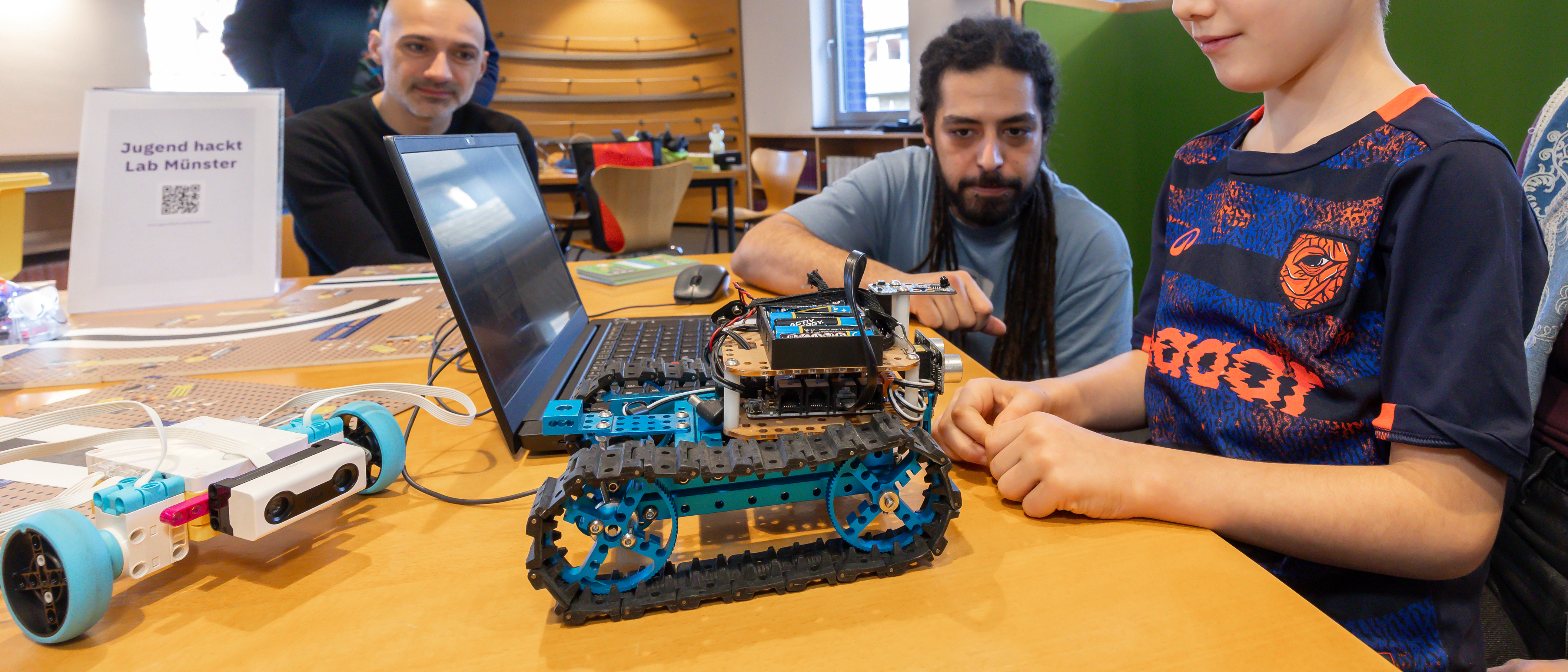 Mentor und Kind an einem Roboter