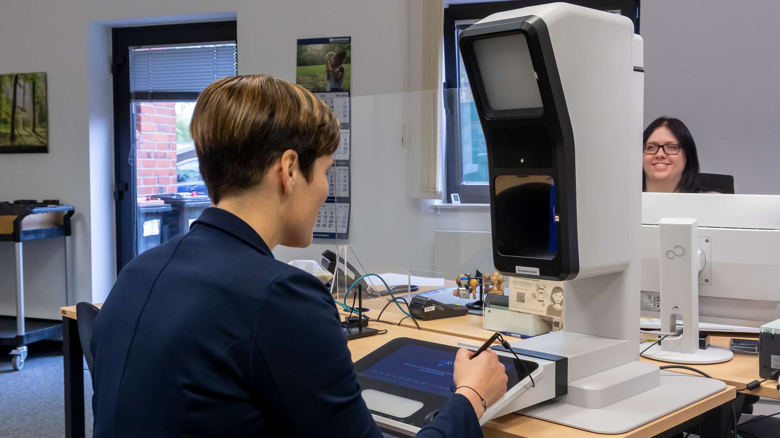 Frau beim Aufnehmen eines Passbildes am neuen digitalen Passbildautomaten