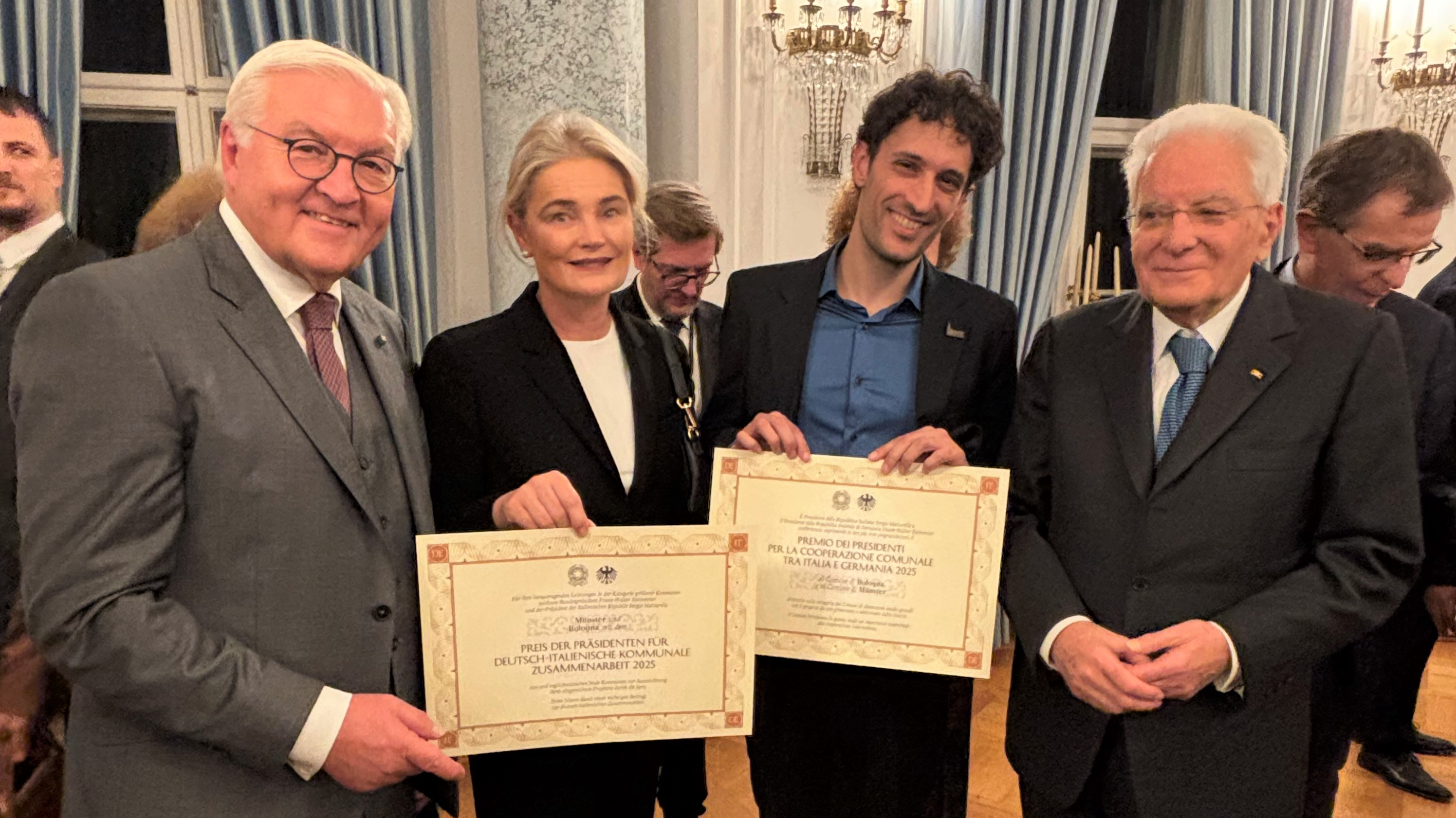 Vier Personen halten zwei Urkunden in der Hand