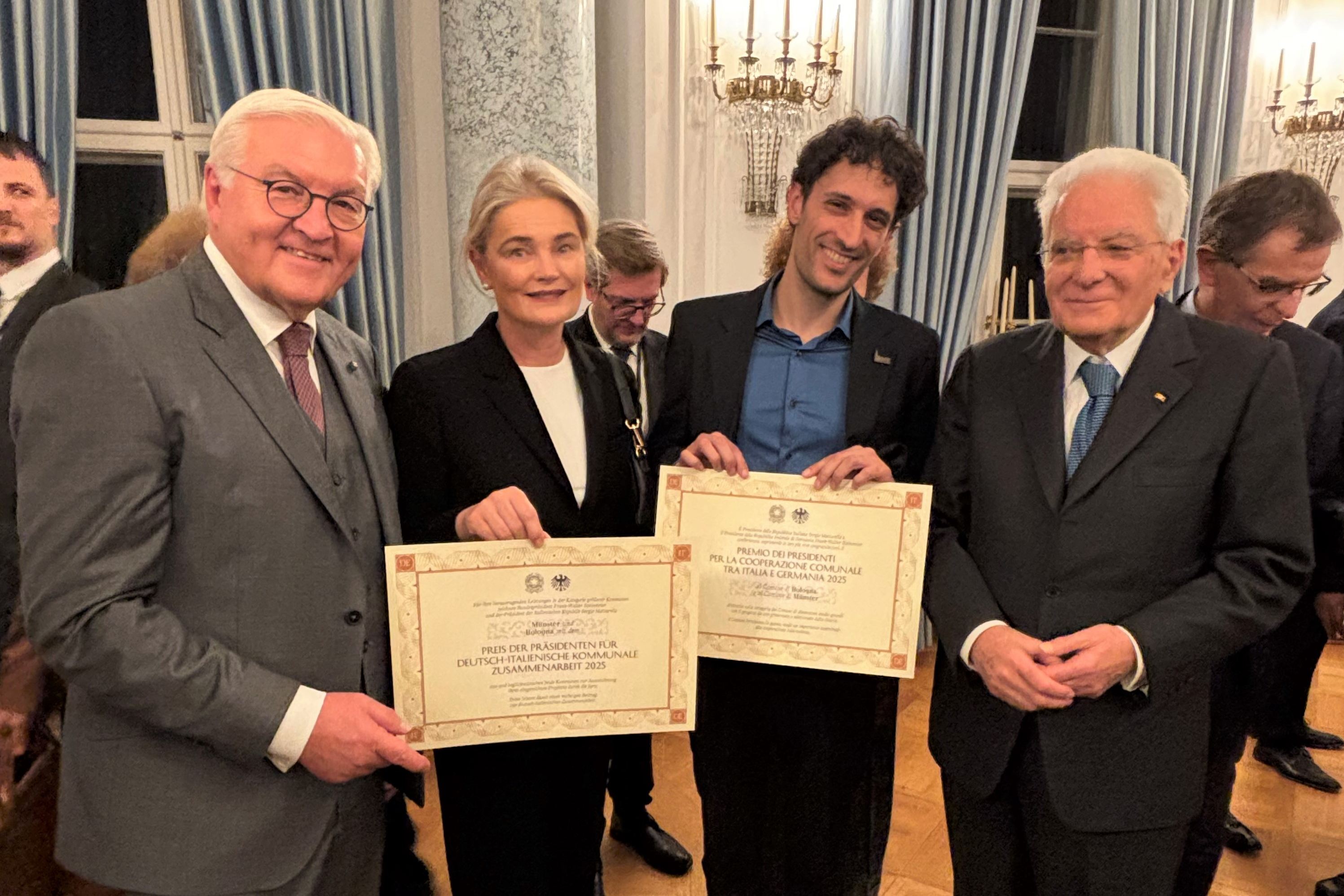 Vier Personen halten zwei Urkunden in der Hand