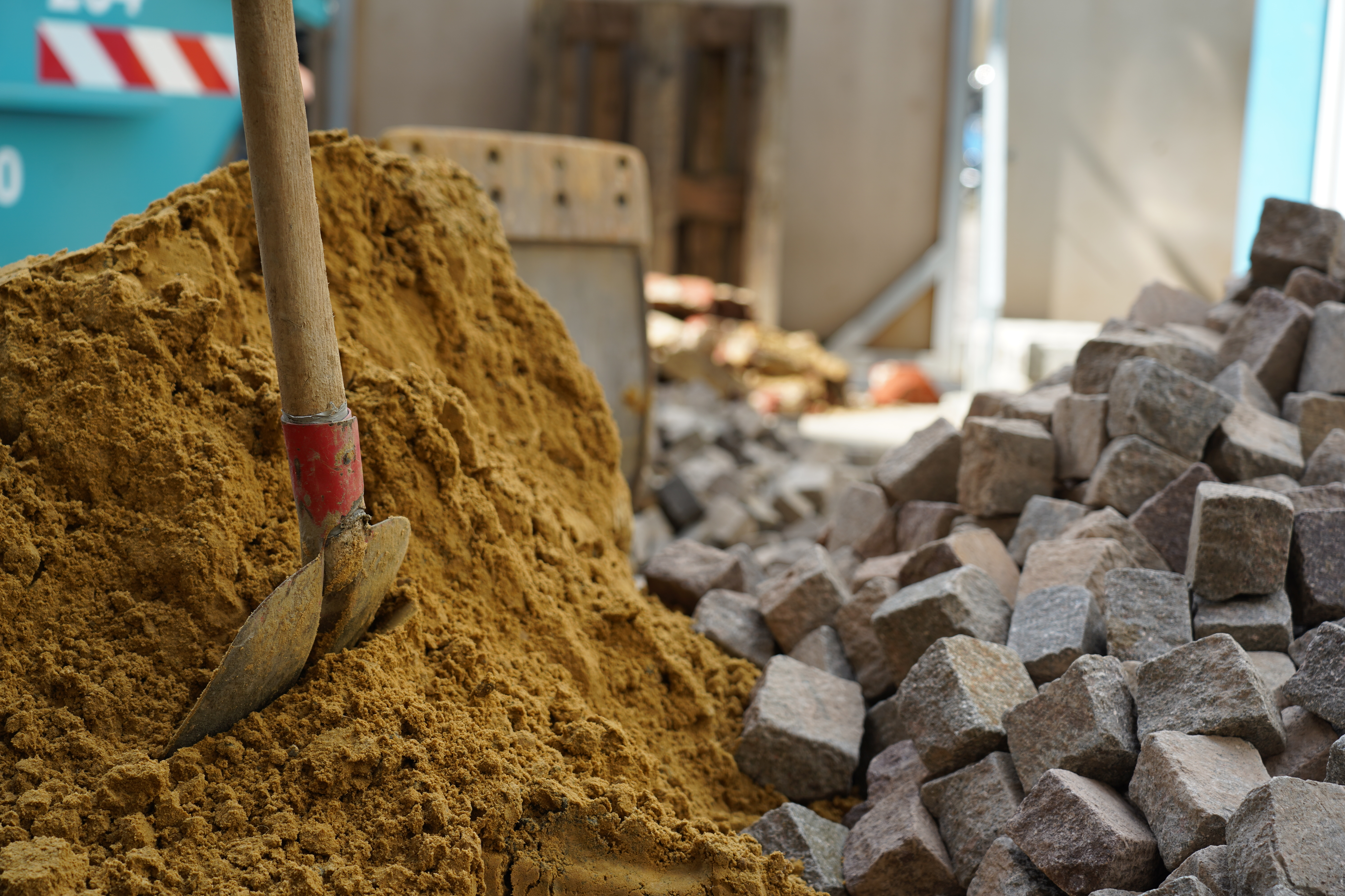 Sand- und Steinhaufen auf einer Baustelle mit einer Schaufel