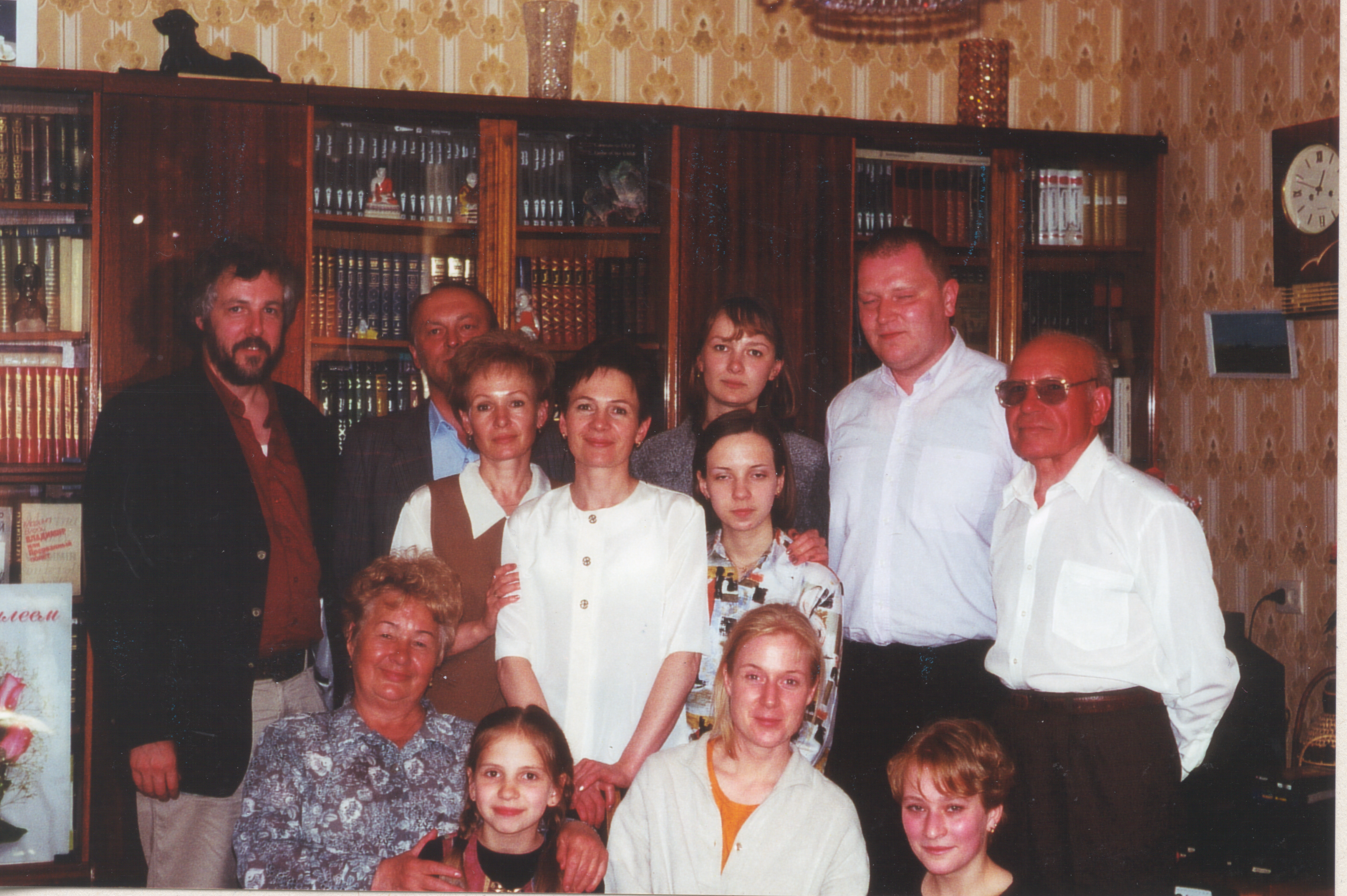 Zwölf Personen stehen vor einem Bücherregal in eine Privatwohnung und lächeln in die Kamera.