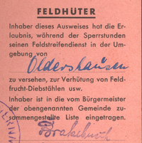 Auf dem roten Ausweisdokument steht auf Englisch und Deutsch unter anderem folgender Hinweis: 'Feldhüter. Inhaber dieses Ausweises hat die Erlaubnis während der Sperrstunden seinen Feldstreifendienst in der Umgebung von Oldershausen zu versehen, zur Verhütung von Feldfrucht-Diebstählen usw.'