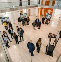 Ein Blick von oben auf einen offenen Raum in der Bezirksregierung Münster mit Ausstellungsstelen und Menschen, die sich die Plakate an den Stelen anschauen und im Gespräch miteinander sind.