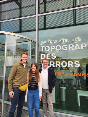 Drei Personen stehen vor einer Glasfront mit der Aufschrift "Dauerausstellung Topographie des Terrors"