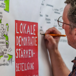 Mann schreibe Lokale Demokratie stärken an die Tafel
