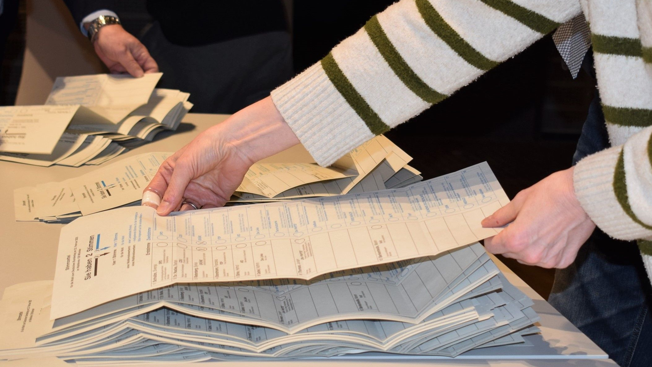 Mehrere Hände auf Stapeln von Wahlzetteln