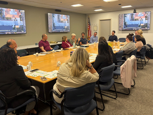 Mehrere Personen sitzen am Tisch und sprechen mit einander