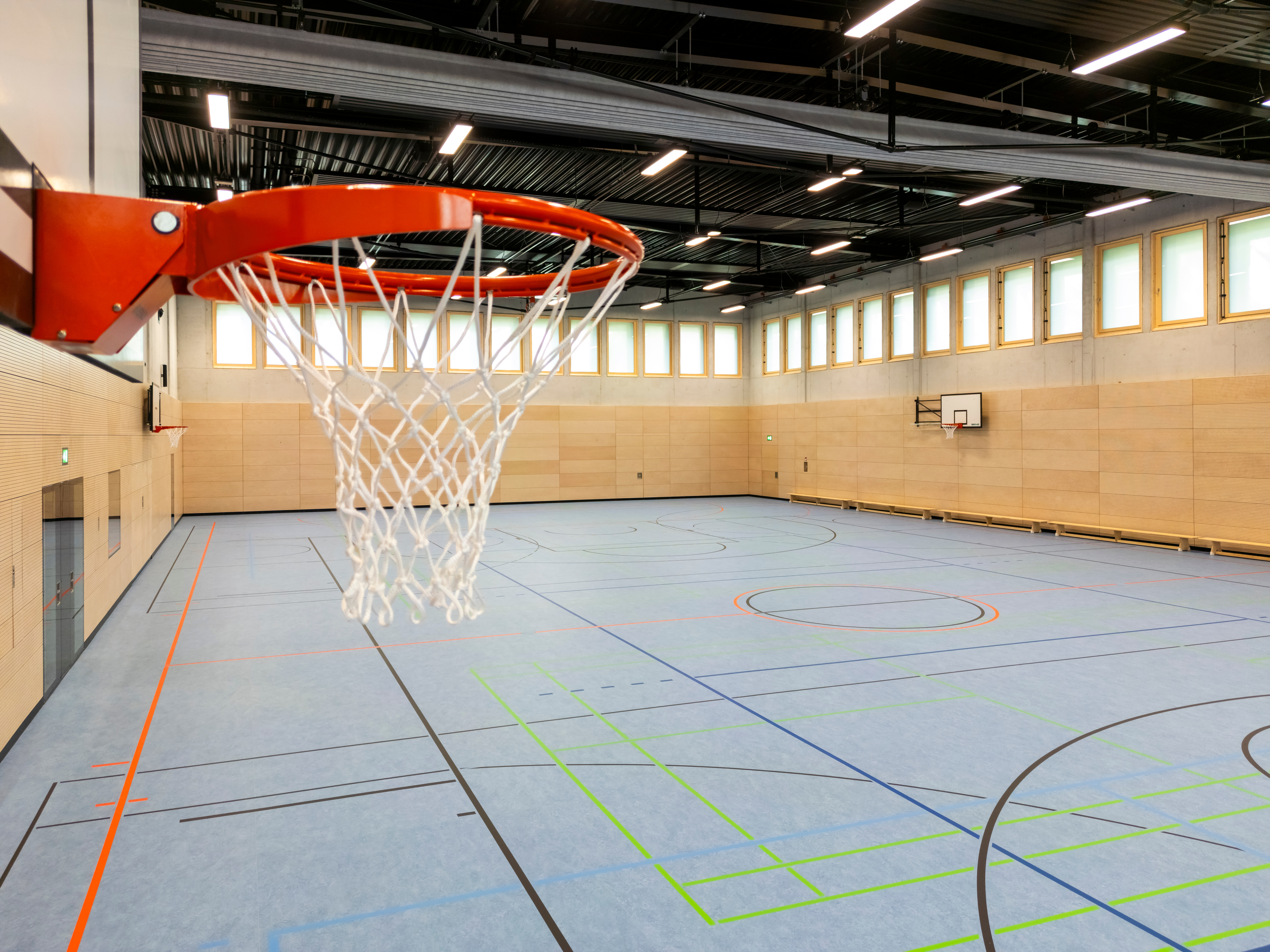 Eine Sporthalle von innen, im Vordergrund des Fotos ist ein Basketballkorb zu sehen.