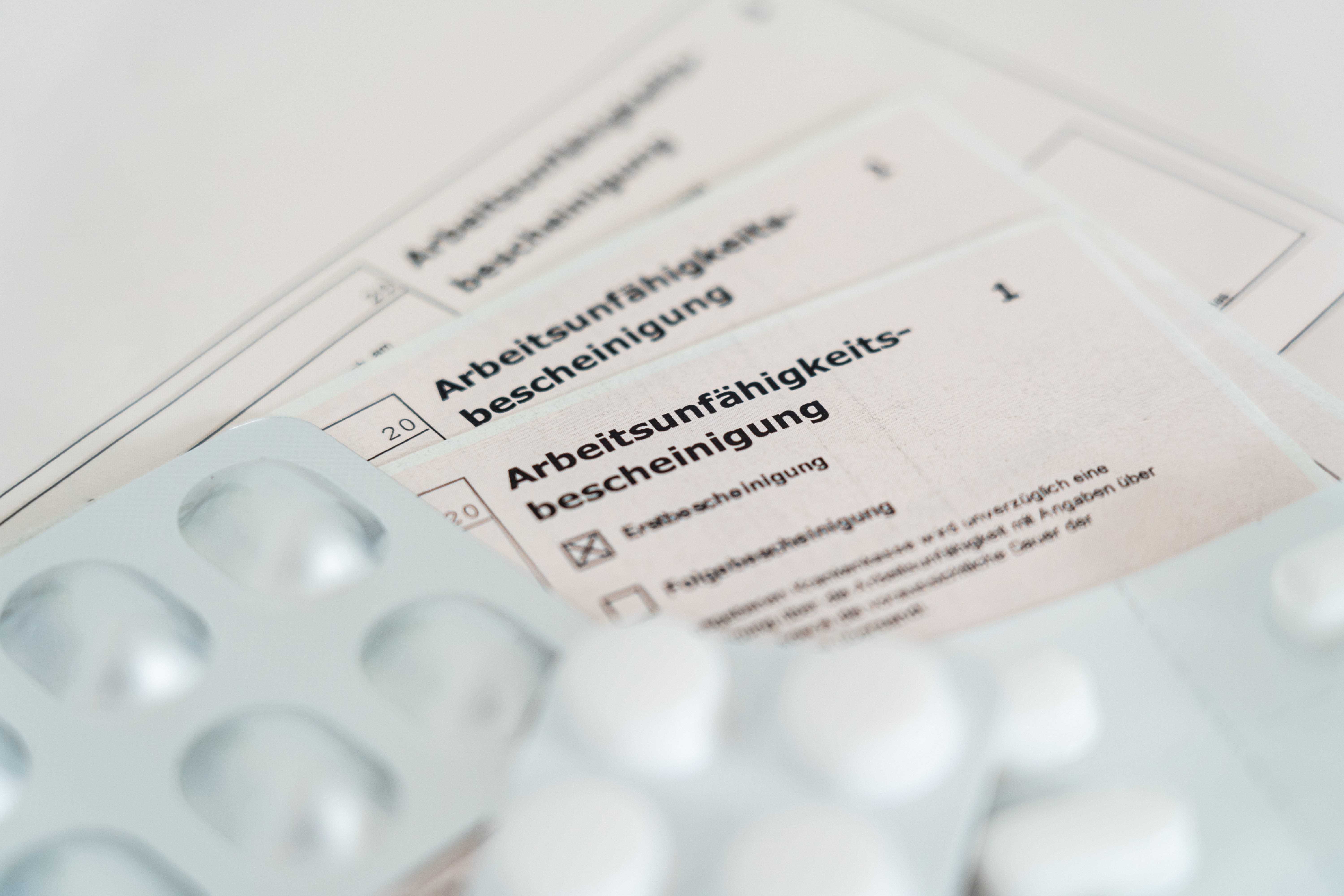 Arbeitsunfähigkeitsbescheinigung mit Blistern an Tabletten, die darauf platziert sind