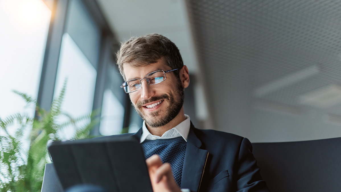 Junger Mann im Anzug schaut auf Tablet-PC