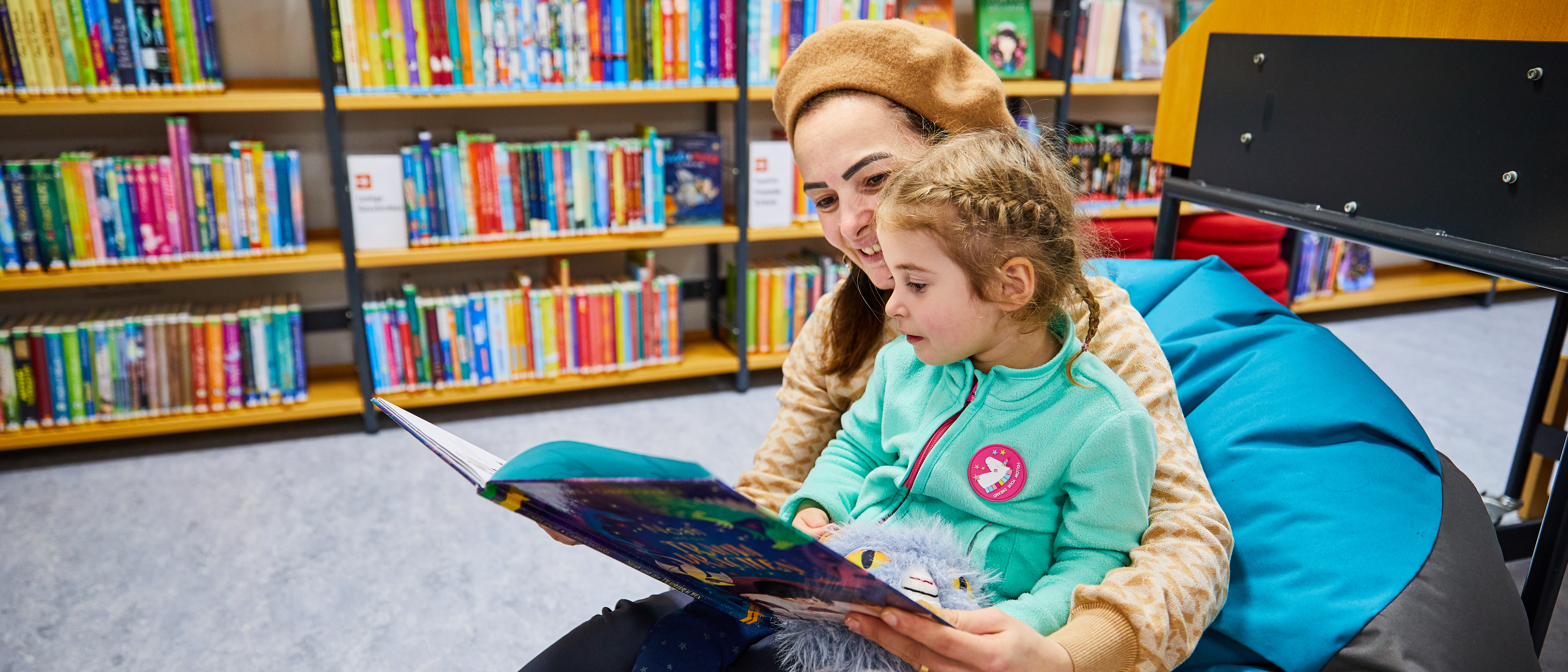 Mutter mit Kleinkind auf dem Schoß und Buch ind er Hand