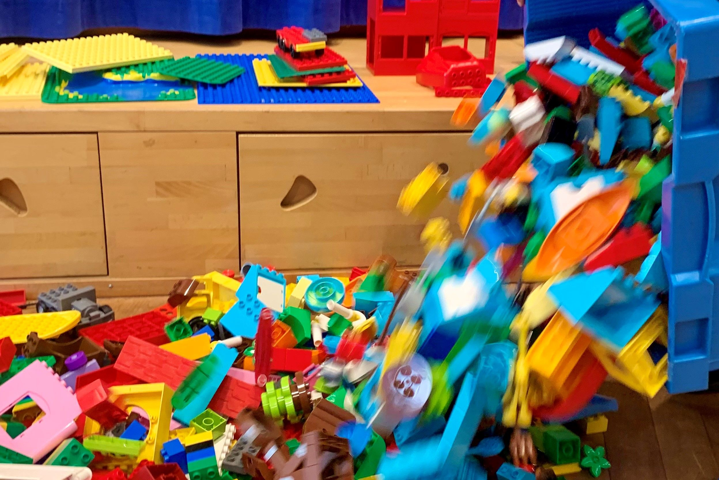 Aus einer Kiste werden LEGO® DUPLO® Steine ausgeschüttet.