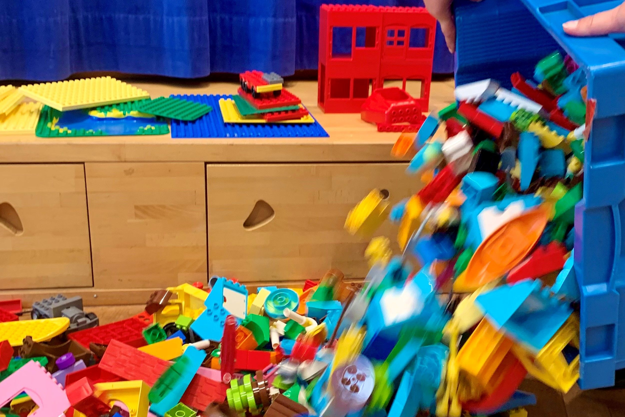 Aus einer Kiste werden Lego® DUPLO® Steine ausgeschüttet.