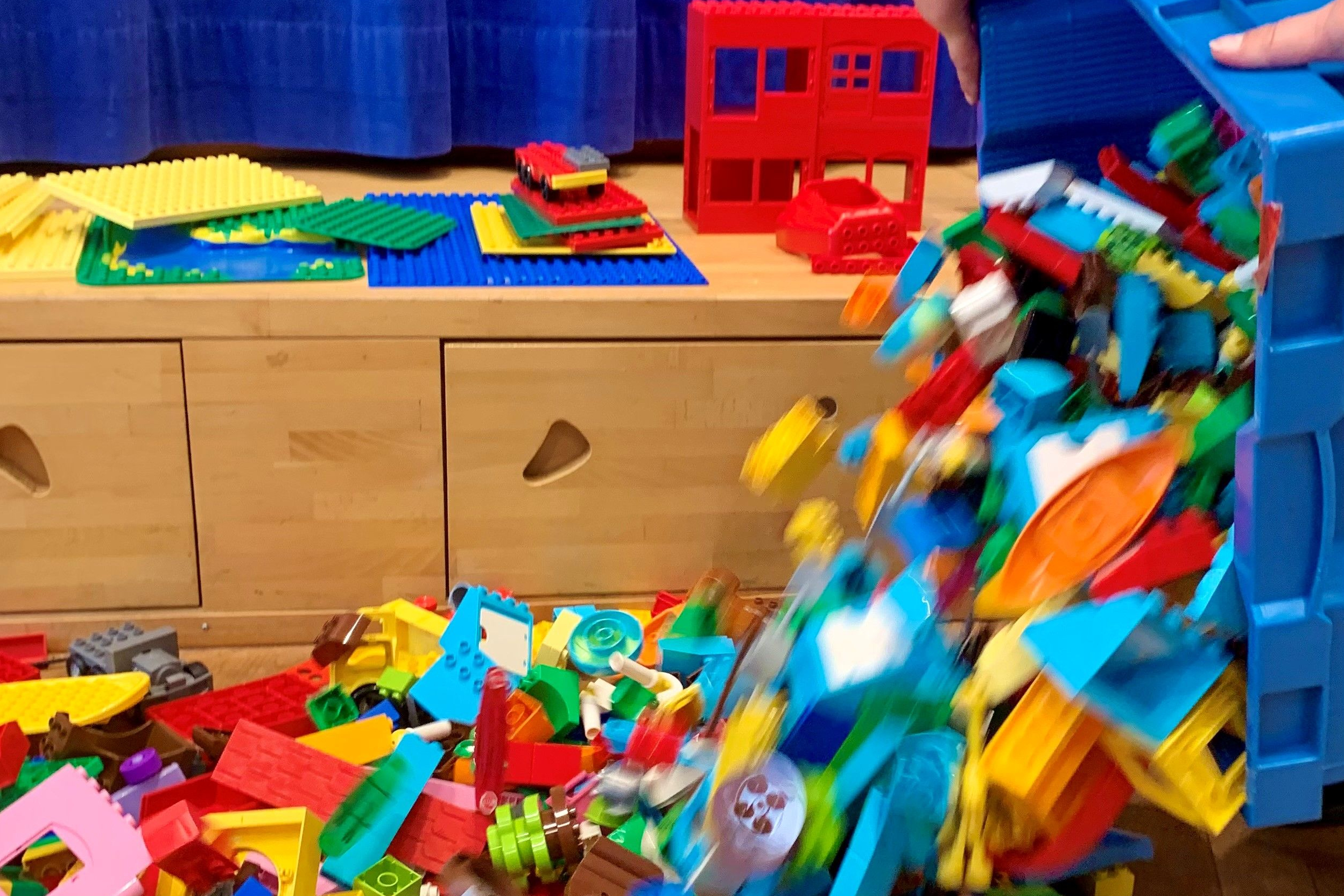 Aus einer Kiste werden Lego® DUPLO® Steine ausgeschüttet.