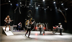 Performer*innen mit Zweirädern und Instrumenten auf der Bühne.