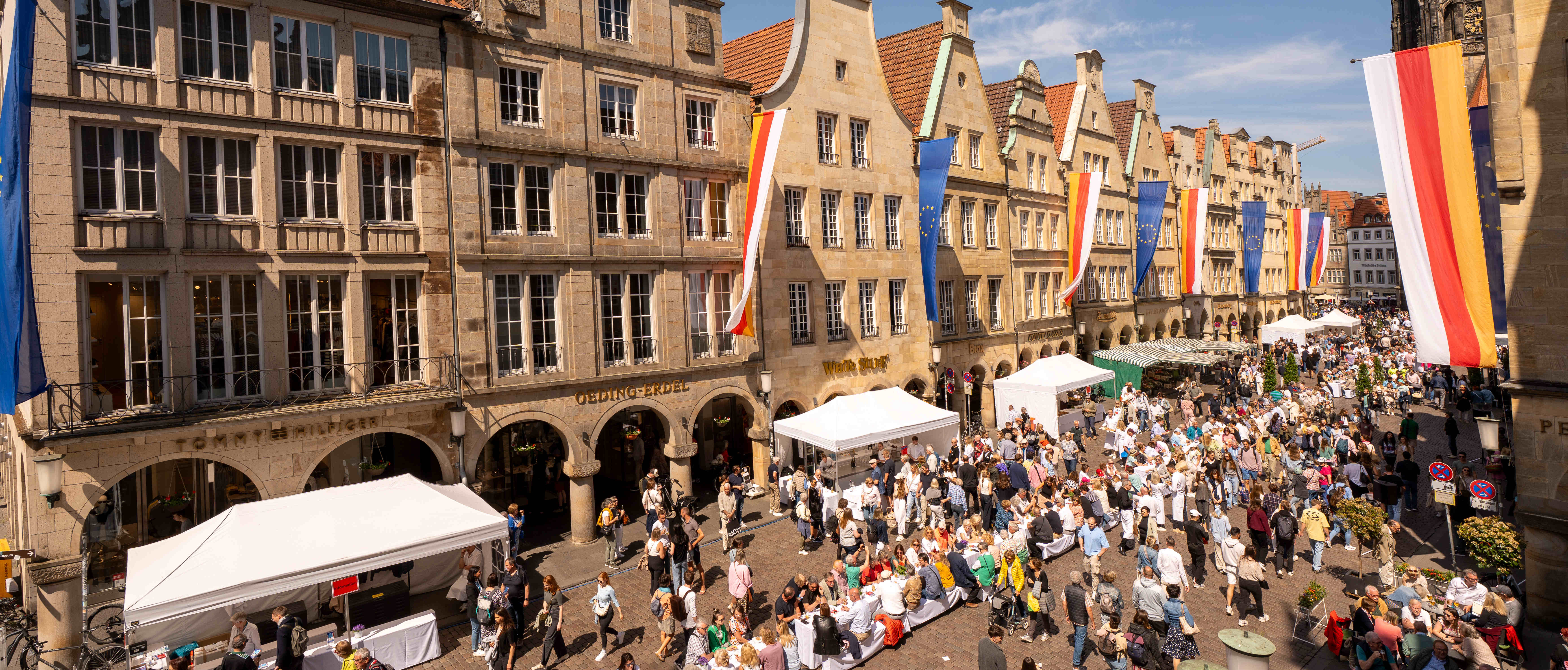 Zum Hansemahl 2025 steht eine lange Tafel auf dem Prinzipalmarkt, an der viele Menschen Platz genommen haben.