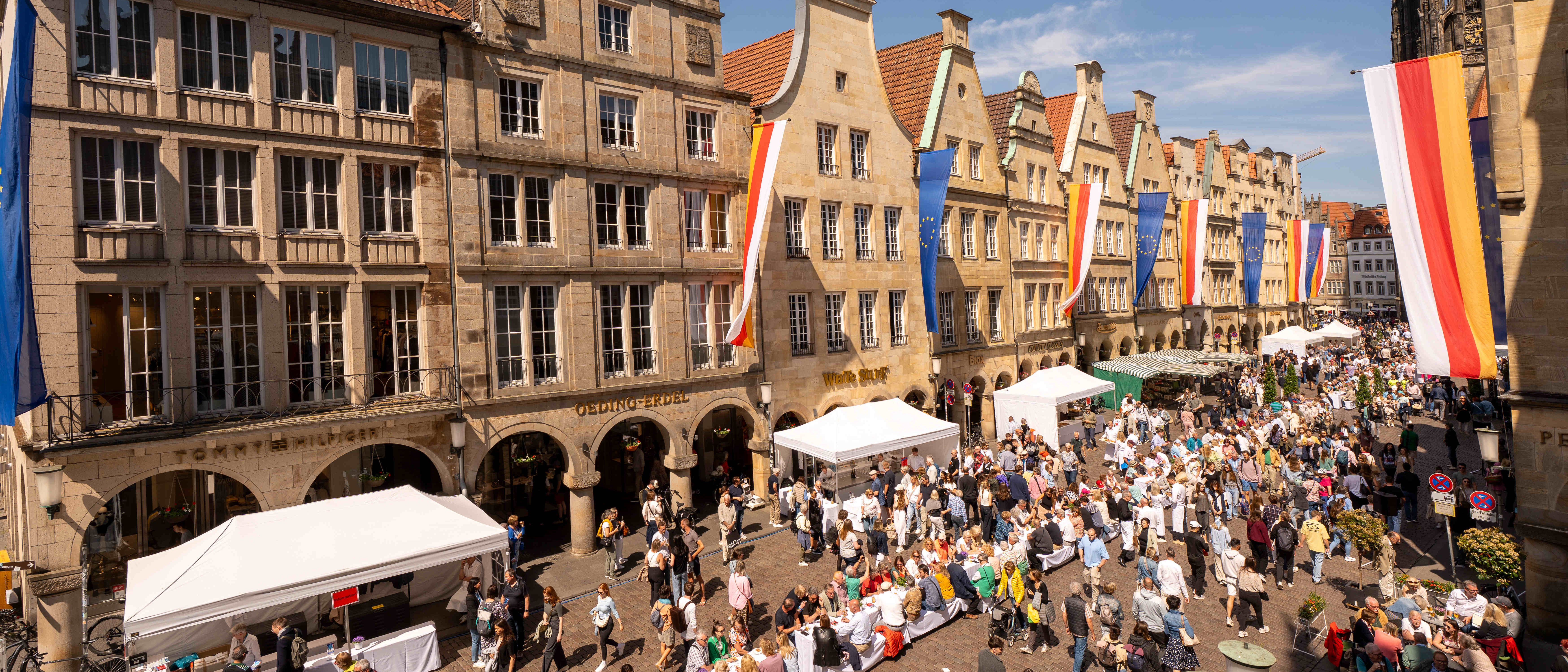 Zum Hansemahl 2025 steht eine lange Tafel auf dem Prinzipalmarkt, an der viele Menschen Platz genommen haben.