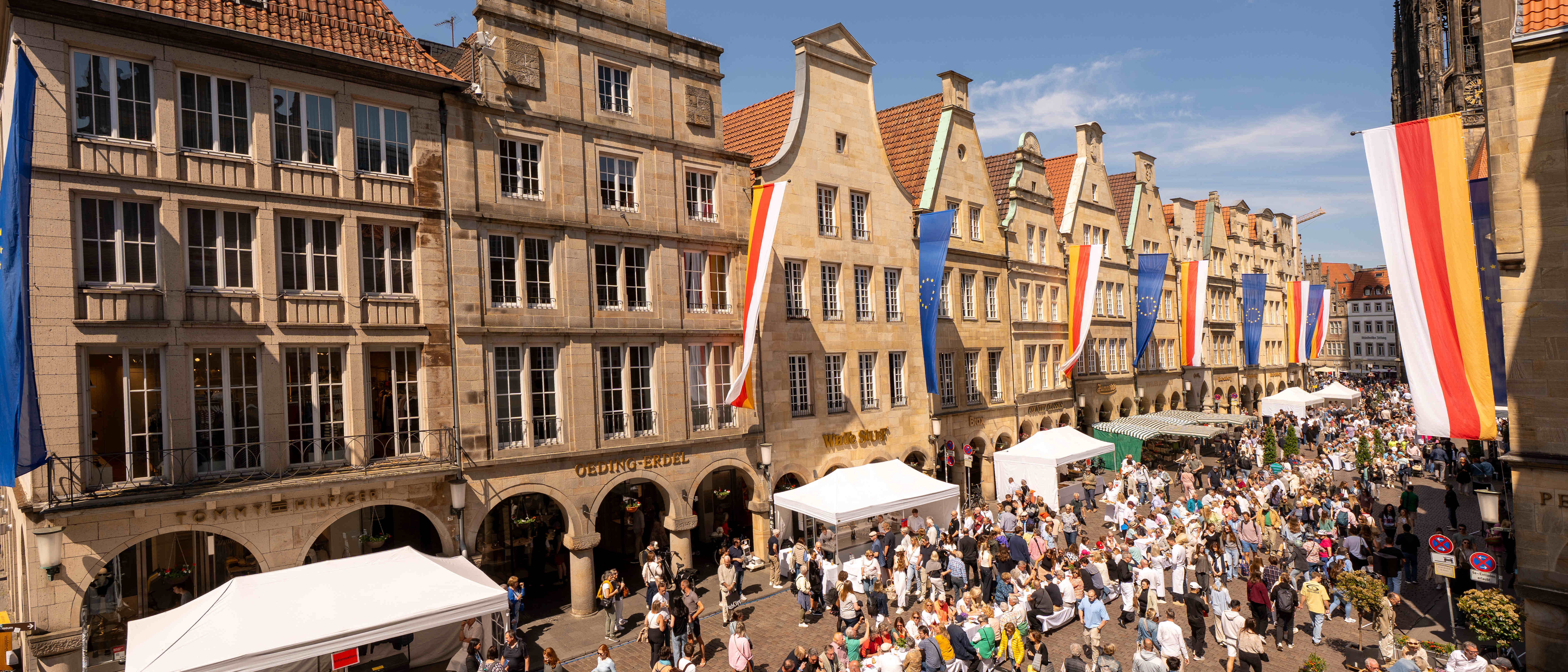 Zum Hansemahl 2025 steht eine lange Tafel auf dem Prinzipalmarkt, an der viele Menschen Platz genommen haben.