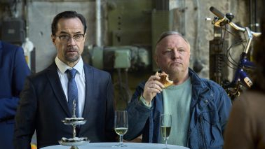 Professor Boerne (Jan Josef Liefers) und Hauptkommissar Thiel (Axel Prahl) führen bei einem Glas Sekt Beobachtungen durch