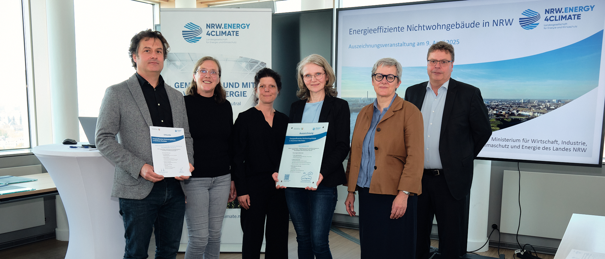 Freuen sich über die Auszeichnung für die Kita Hobbeltstraße (v. l.): Marc Dresen (Hansen + Partner Ingenieure), Maria Fischer, Susanne Hellmann und Michaela Selberg (alle Amt für Immobilienmanagement) sowie Silke Krebs (Staatssekretärin im Ministerium für Wirtschaft, Industrie, Klimaschutz und Energie des Landes NRW) und Carsten Petersdorff (Bereichsleiter Wärme & Gebäude NRW.Energy4Climate). 