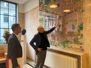 Zwei Männer schauen sich Stadtplan an der großen Wand