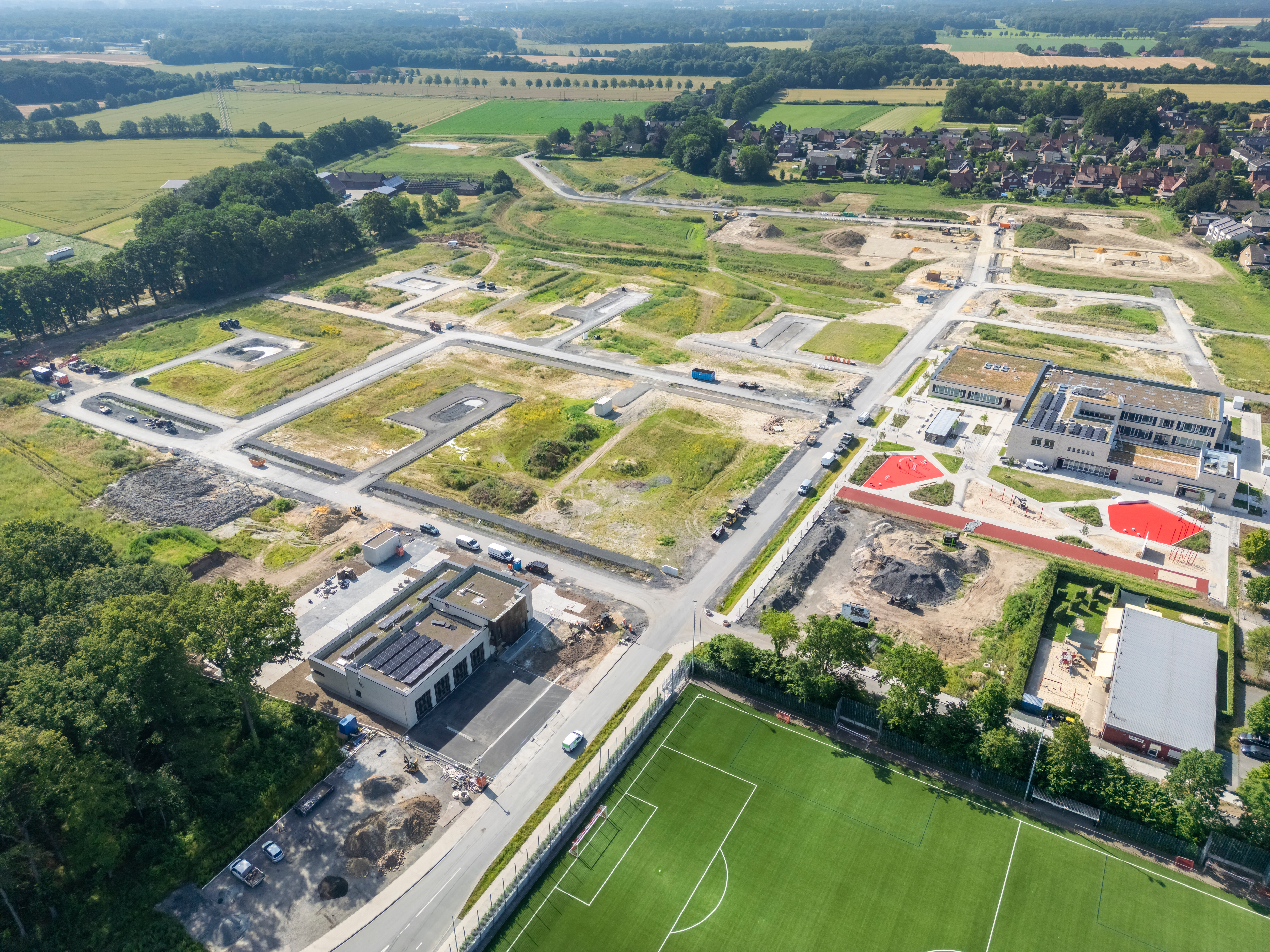Drohnenaufnahme des Geländes auf dem die Baugrundstücke verkauft werden. Aktuell sind dort nur Brachflächen und Straßen zu sehen. 