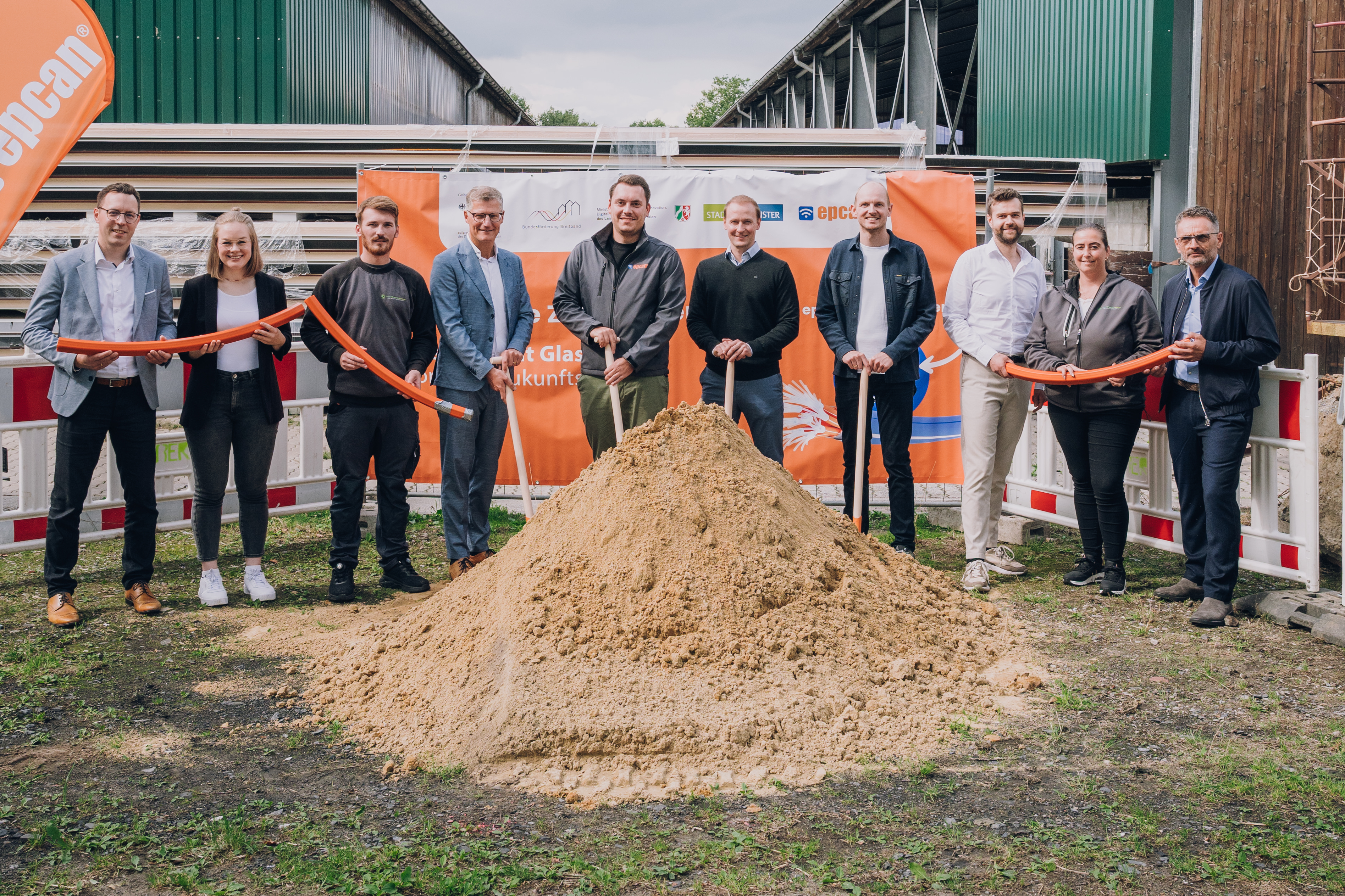 Gruppenbild mit Schaufeln und aufgehäuften Sand