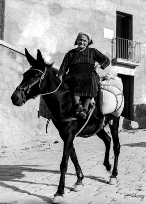 Eine Frau mit Säcken auf einem Pferd.