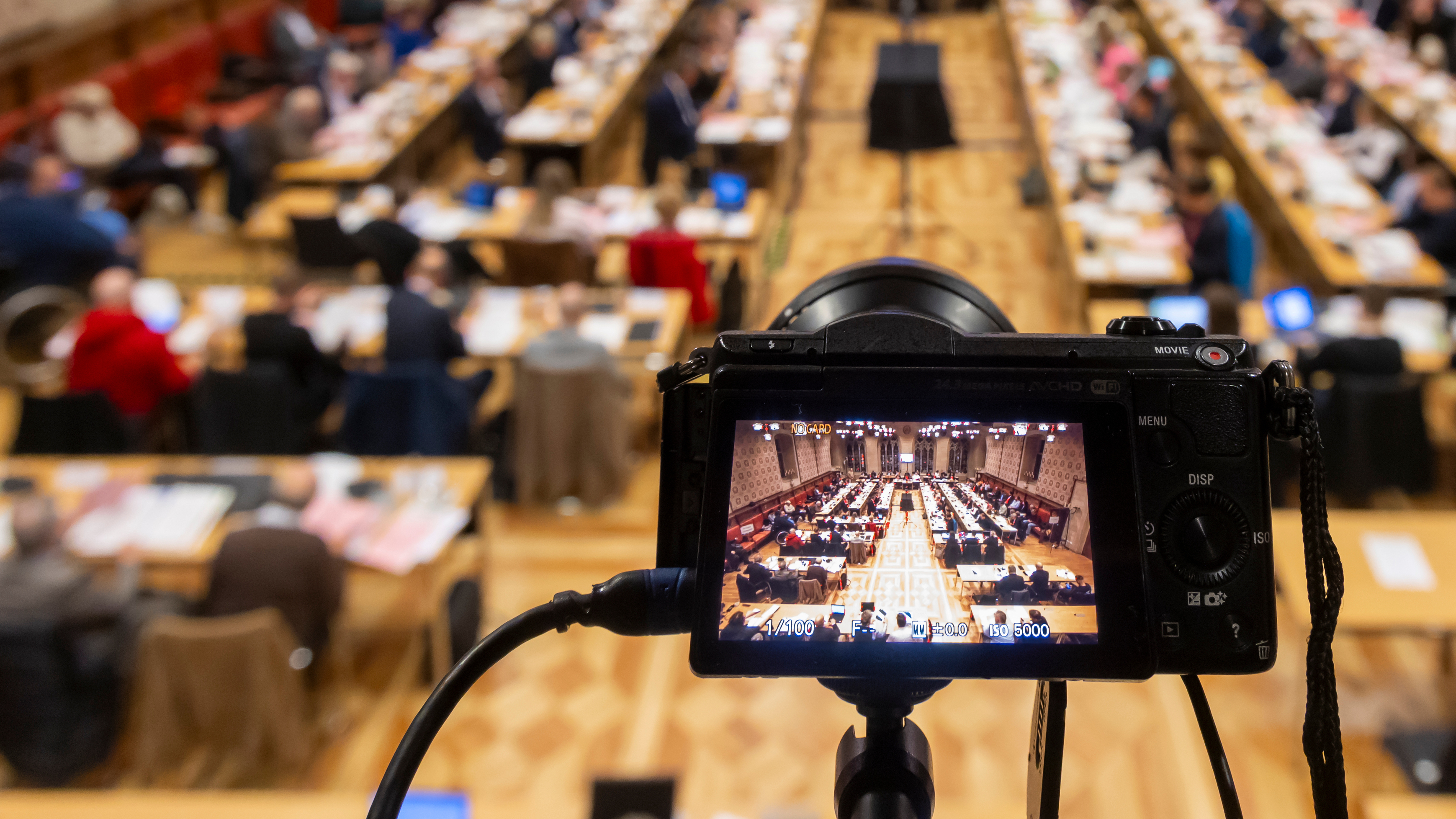 Blick auf die Ratssitzung im Rathausfestsaal, im Vordergrund eine Kamera, die ebenfalls auf die Sitzung gerichtet ist.
