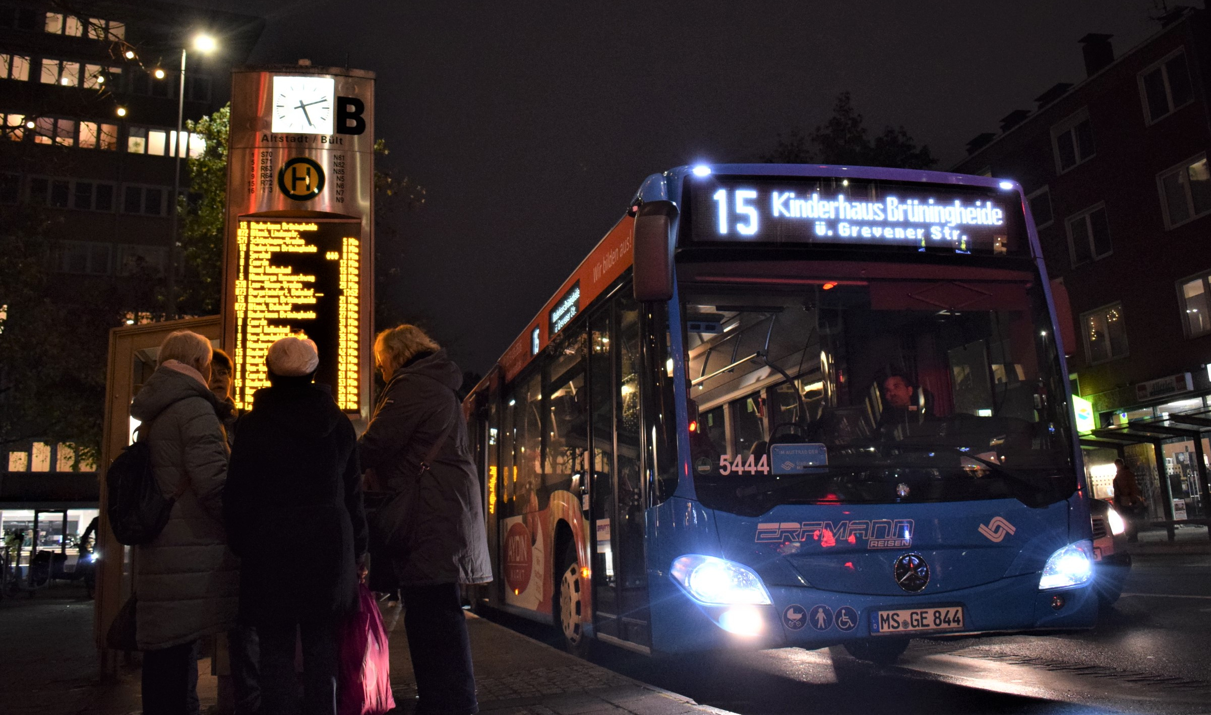 Eine Bushaltestelle bei Dunkelheit, ein Bus hält gerade an