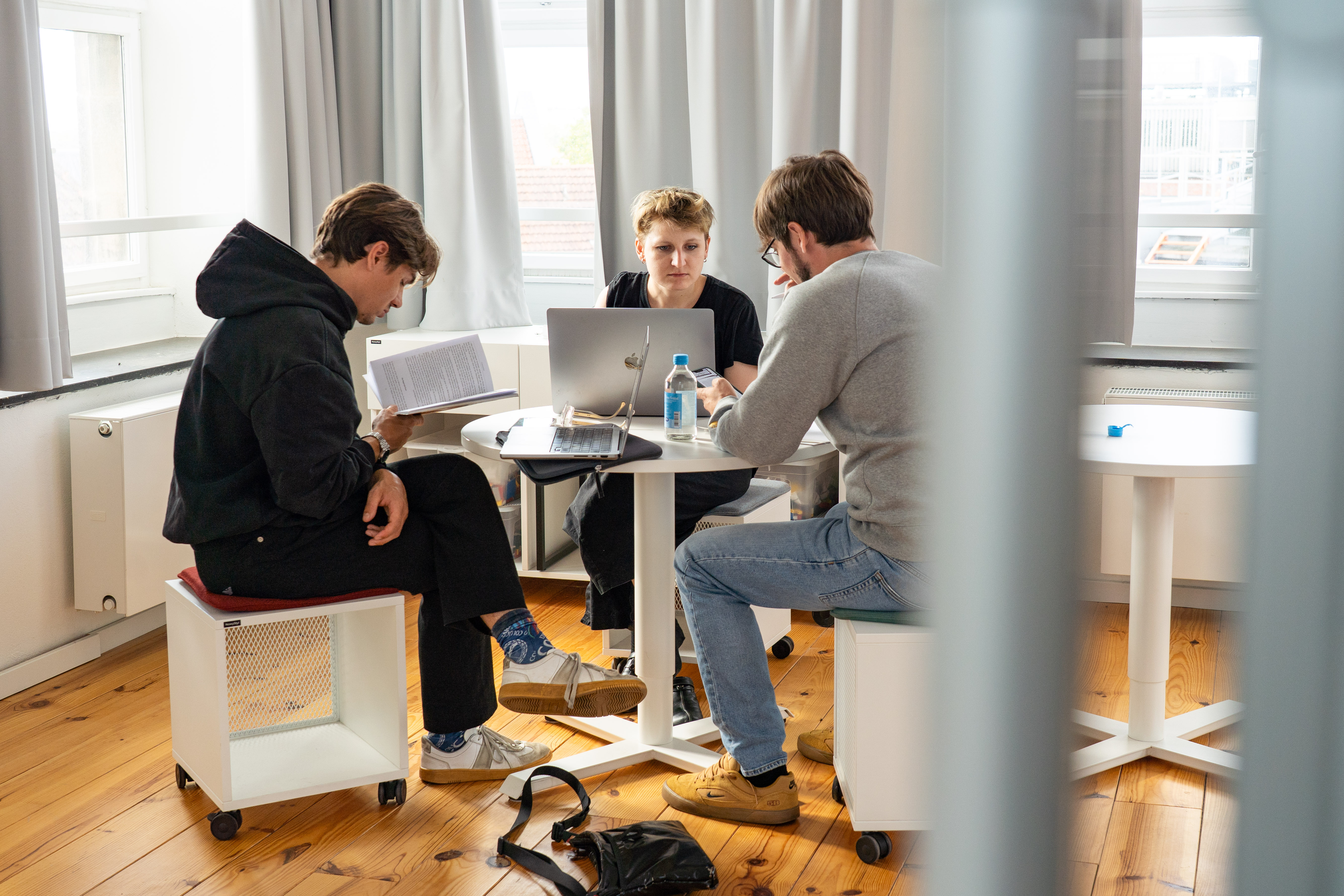 Drei Workshopteilnehmende sitzen mit Laptops an einem Tisch