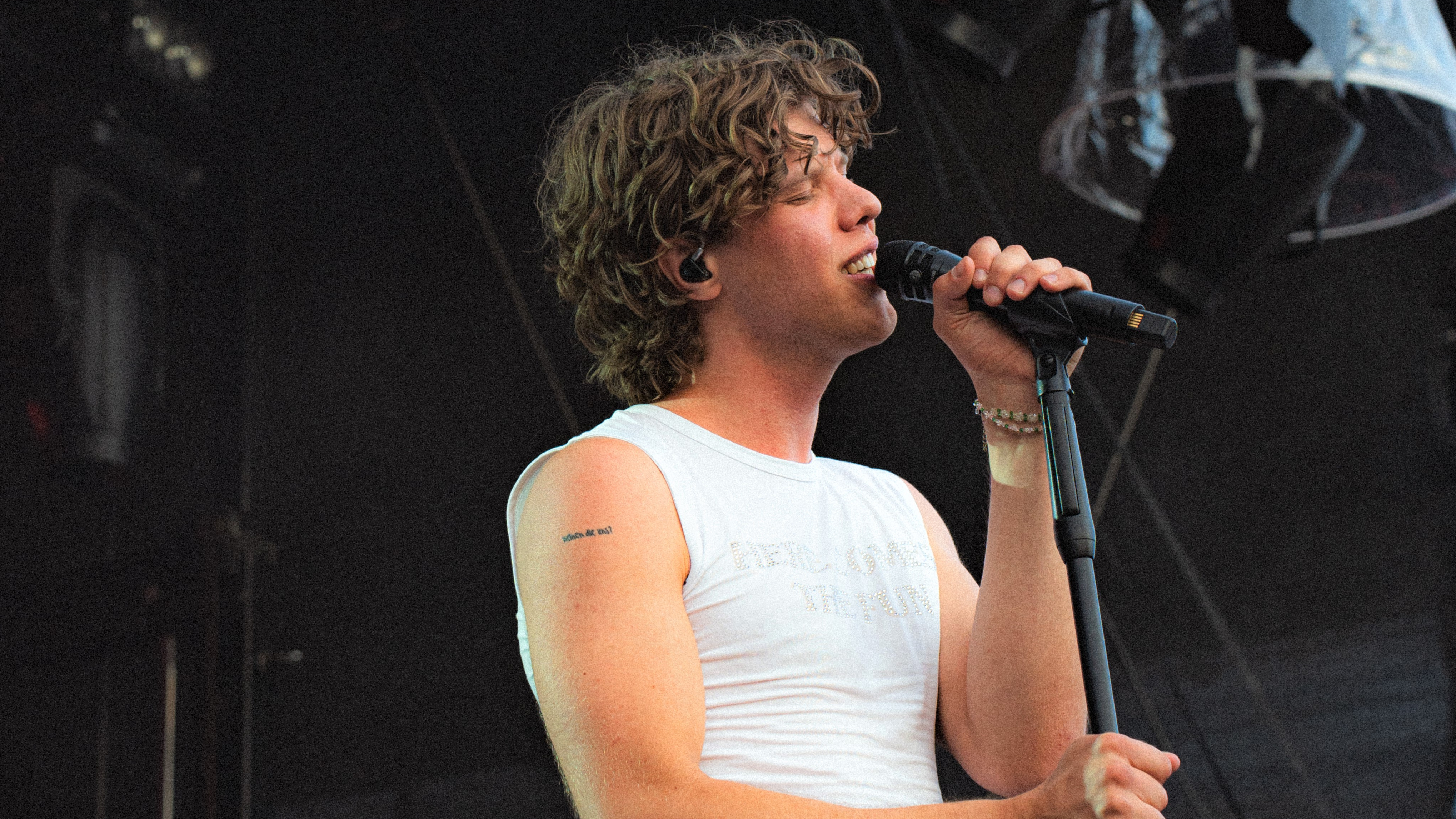 Junger Mann mit Locken auf einer Bühne mit Mikrofon