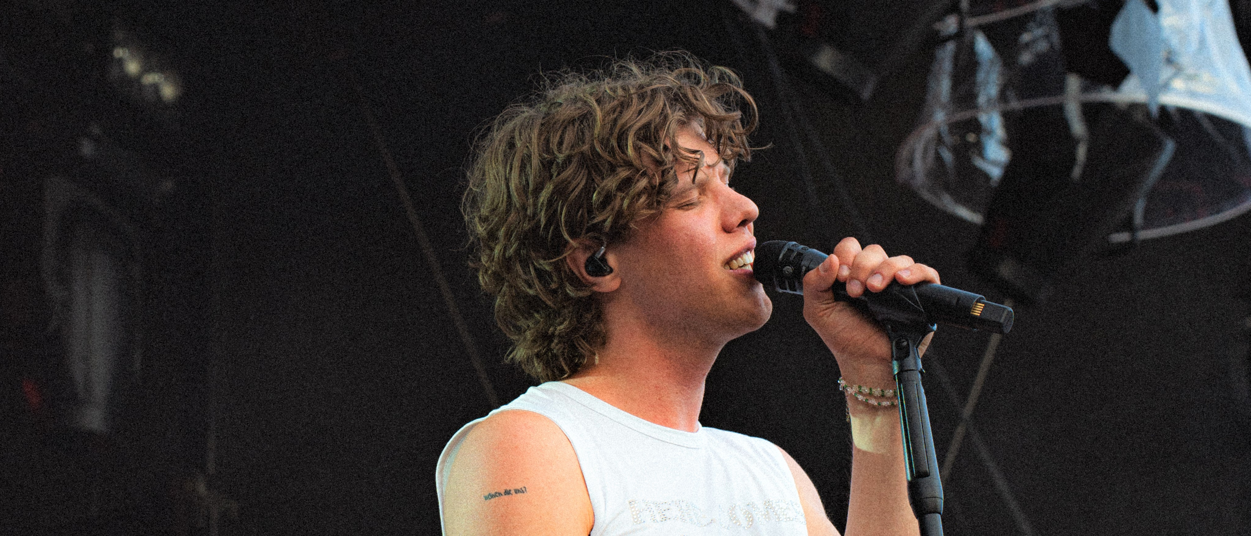 Junger Mann mit Locken auf einer Bühne mit Mikrofon