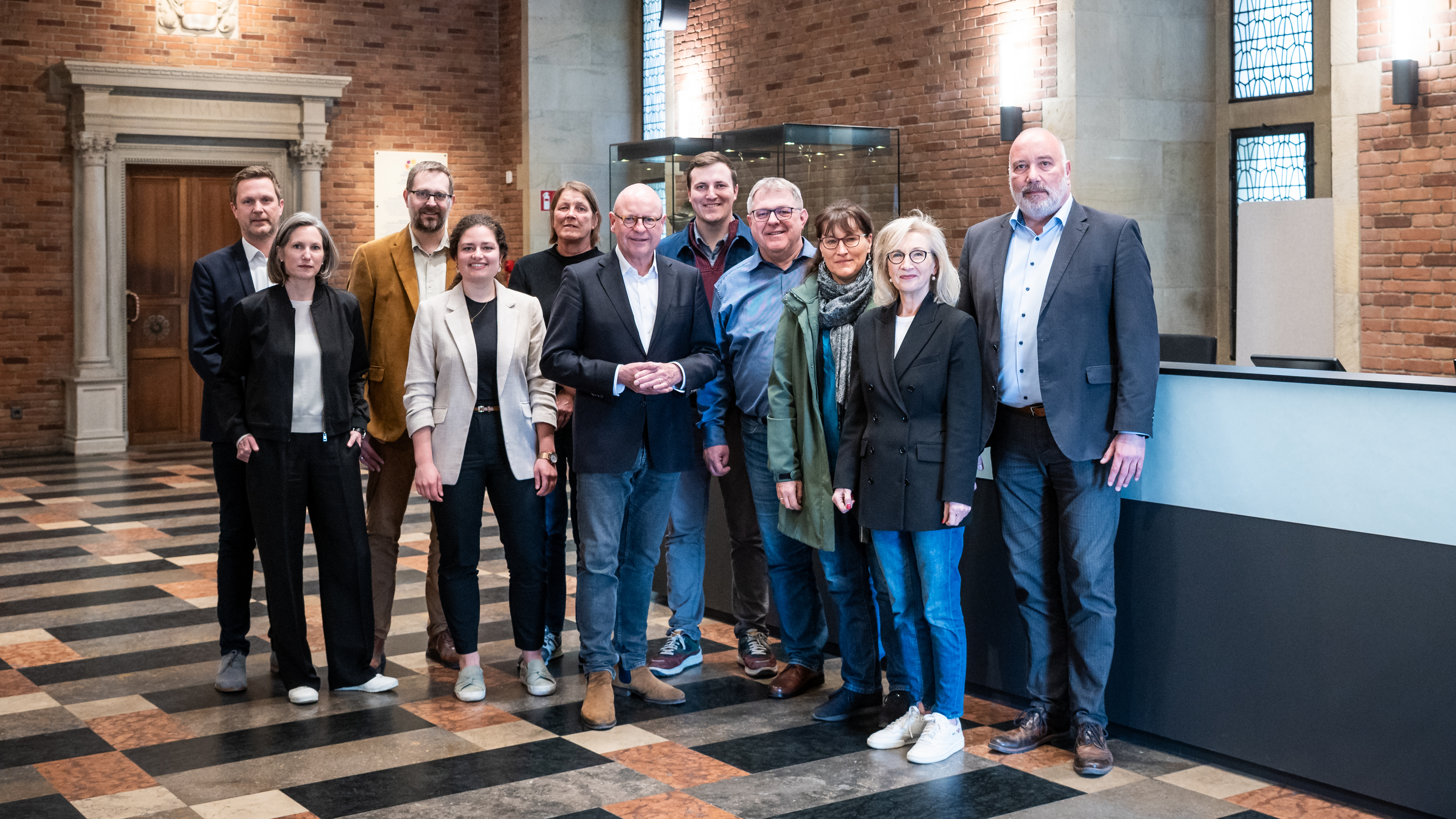 Oberbürgermeister Markus Lewe (6. v. l.), Immobiliendezernent Arno Minas (r.), Bernadette Spinnen (Leiterin Münster Marketing) (2. v. r.) freuen sich gemeinsam mit weiteren Projektbeteiligten aus Politik, Verwaltung und Architekturbüro über den abgeschlossenen Umbau der Bürgerhalle.