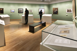 Blick in den Ausstellungsraum, in dem einige Besucher sich die Gemälde anschauen