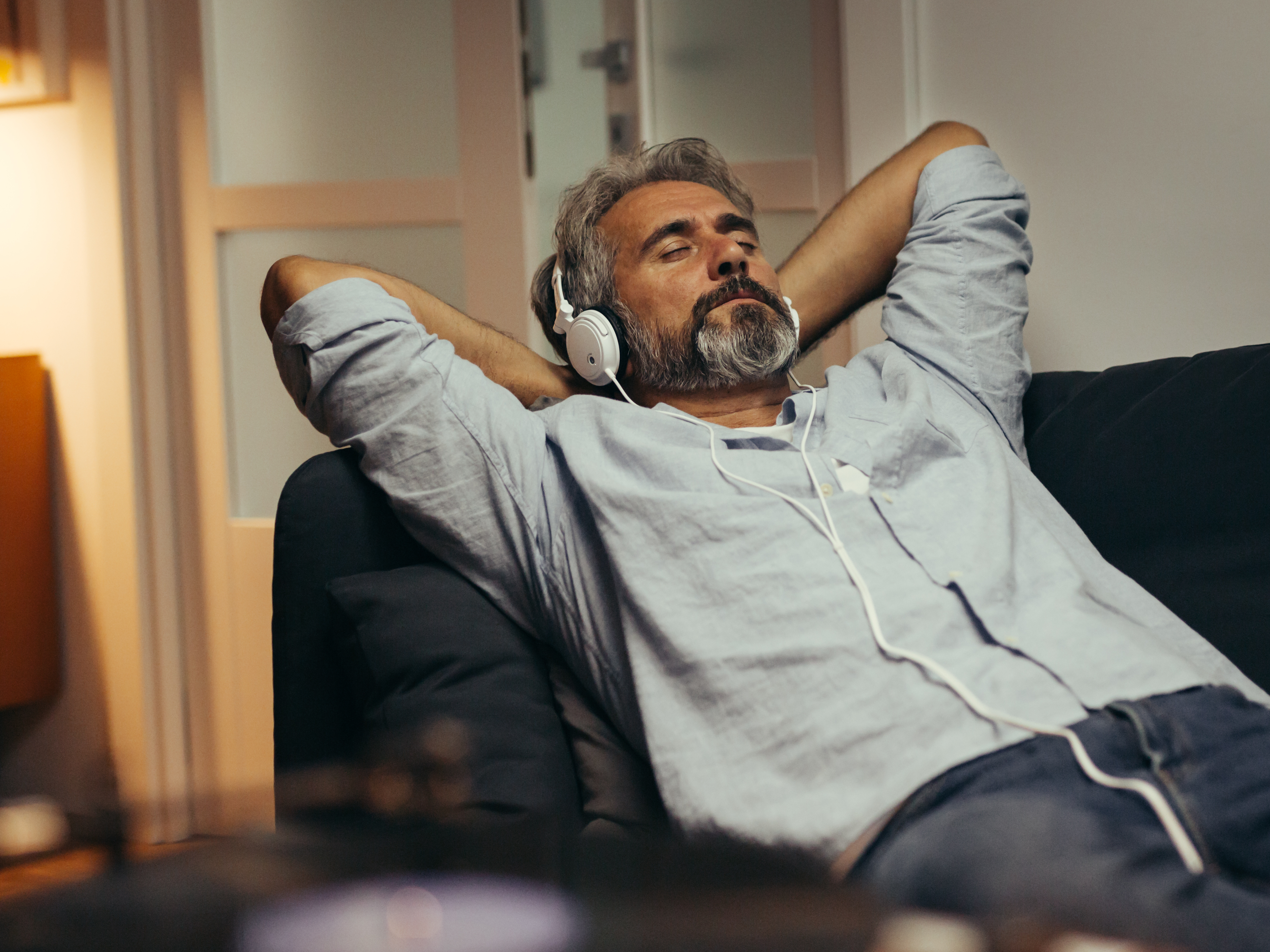 Ein Mann hört über einen Kopfhörer entspannt Musik.