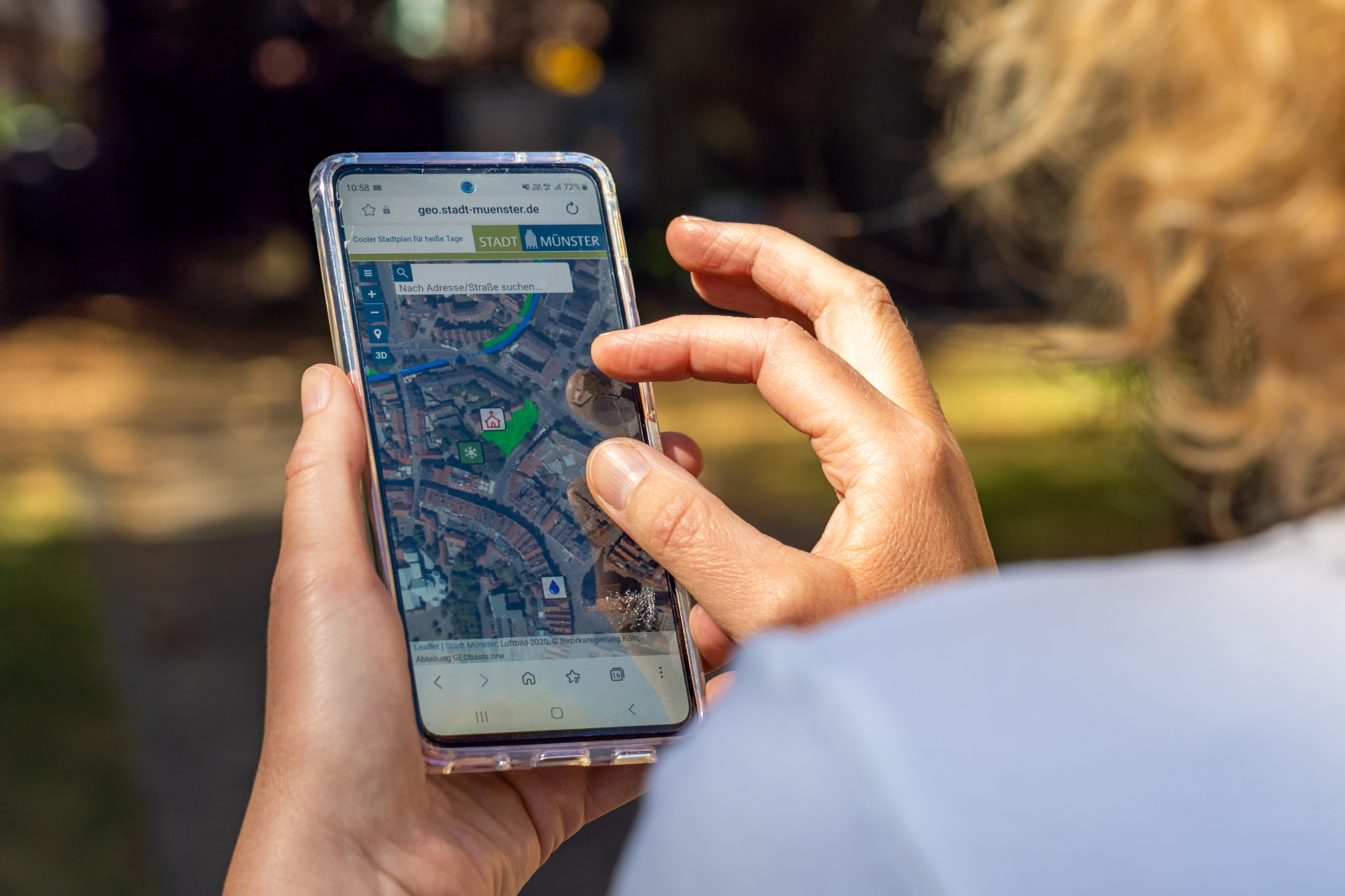 Eine Frau schaut auf ihr Smartphone, auf dem der Coole Stadtplan geöffnet ist