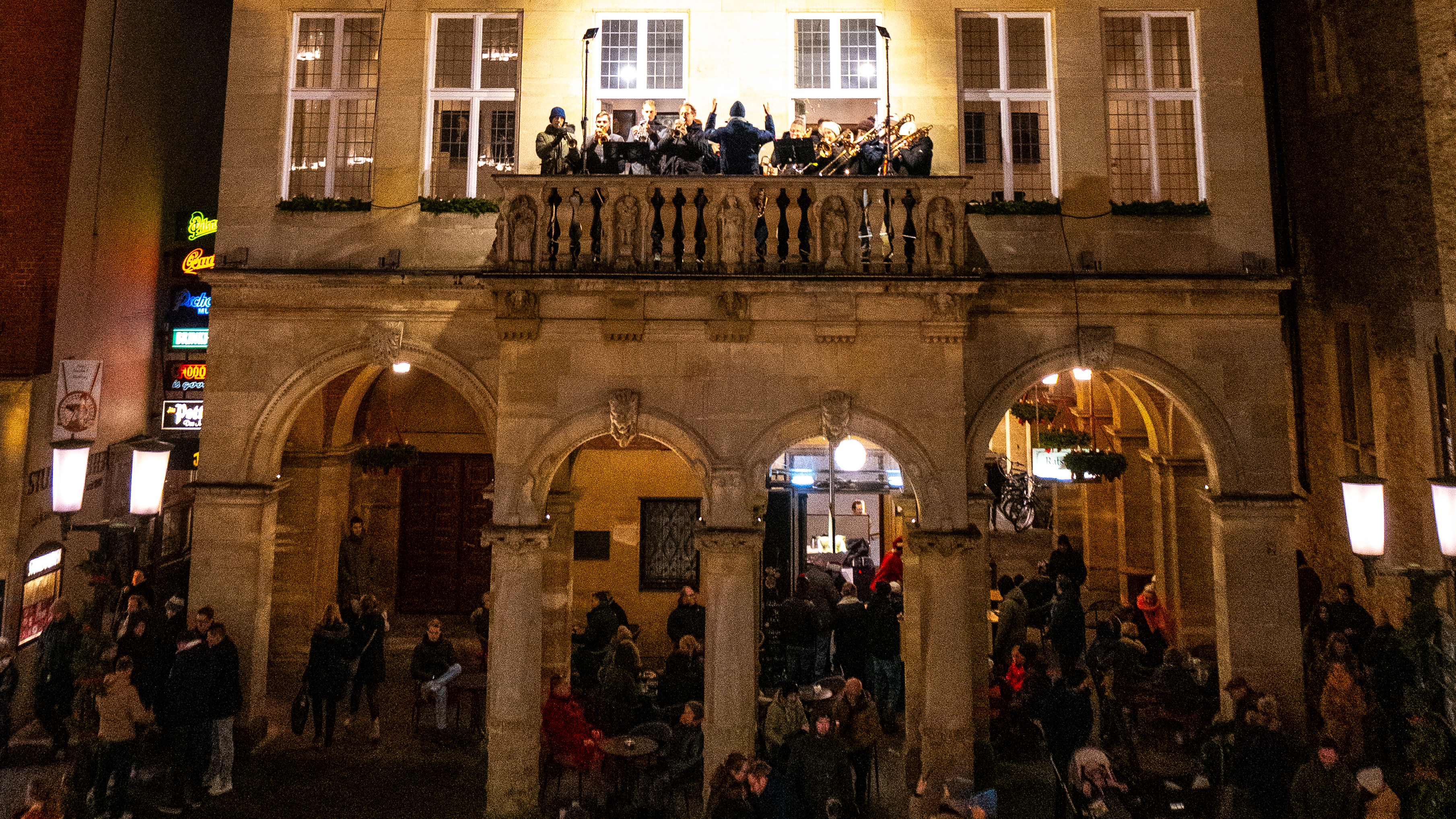 Viele Menschen genießen im Dunkeln ein Konzert vom Sentenzbogen in Münster