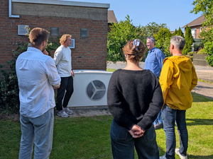 Vier Männer und eine Frau stehen vor einer Wärmepumpe.