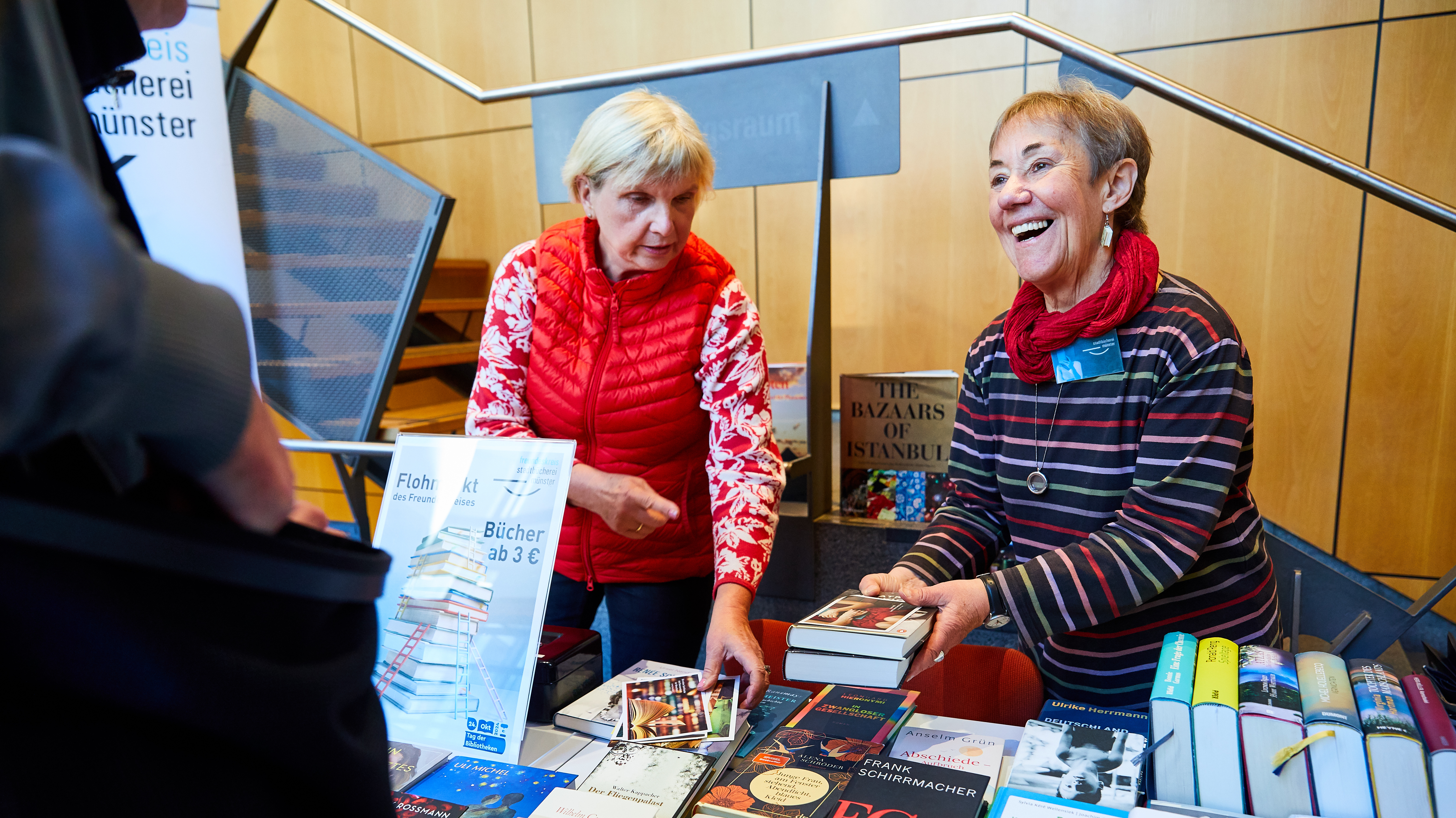 Zwei Frauen an einem Verkaufsstand im Foyer der Stadtbücherei verkaufen Bücher